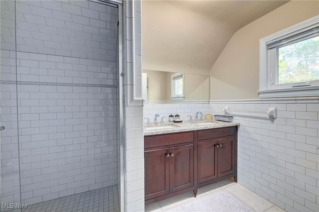 4022 Hillbrook Road Cleveland, OH 44118 - Photo 45 of 49 Full bathroom featuring tile walls, light tile patterned flooring, a shower stall, double vanity, and lofted ceiling