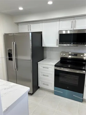 a kitchen with kitchen island a refrigerator and a sink