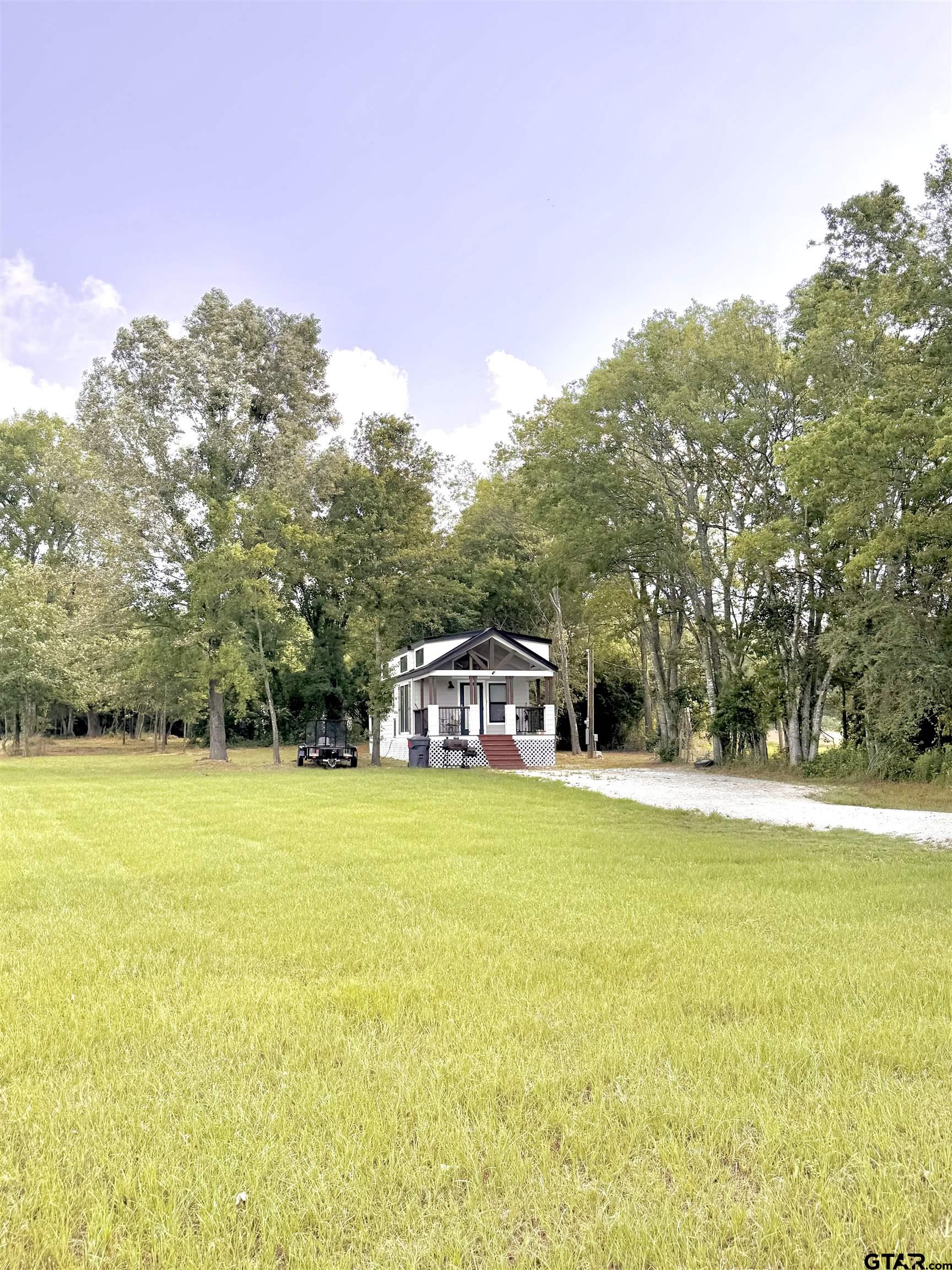 3235 County Road Cookville, TX 75558 - Photo 29 of 38 a view of a large pool with lawn chairs under an umbrella