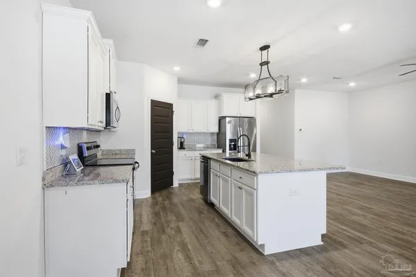 a kitchen with granite countertop a sink stove and refrigerator