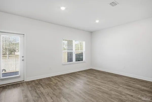 an empty room with wooden floor and windows