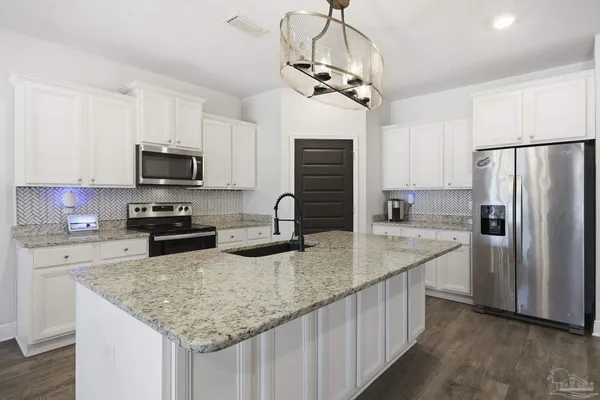 a kitchen with stainless steel appliances granite countertop a sink refrigerator stove and microwave