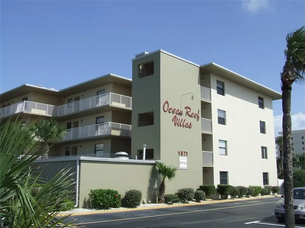 a front view of a building with a garden and entryway