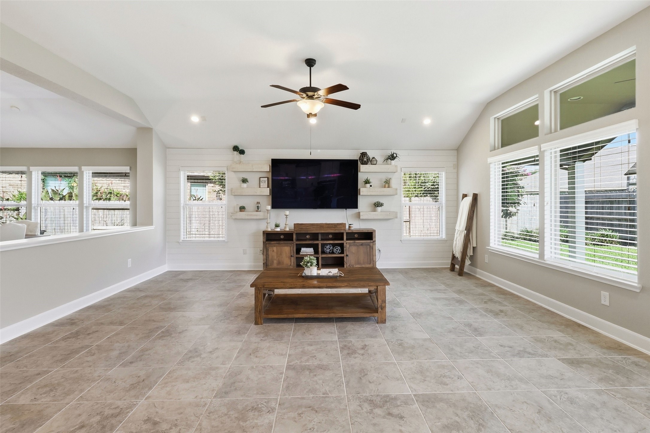 24126 Cane Fields Road Katy, TX 77493 - Photo 14 of 36 Inviting living room featuring a custom shiplap accent wall with floating shelves, creating a warm and stylish focal point.