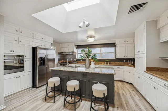 a kitchen with stainless steel appliances granite countertop a table chairs refrigerator and cabinets