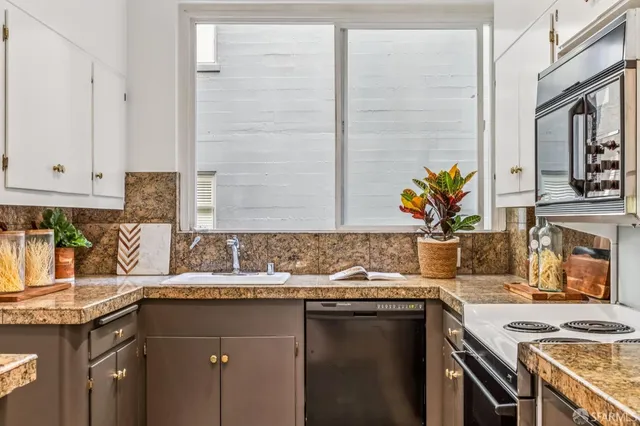 a kitchen with granite countertop a sink a stove and cabinets