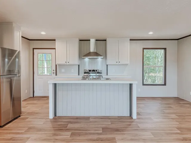 a kitchen with kitchen island granite countertop a stove a refrigerator and a sink with wooden floors