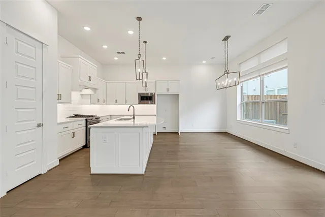 a large white kitchen with lots of counter space wooden floor and appliances