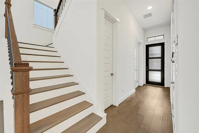 a view of a hallway with wooden floor and windows
