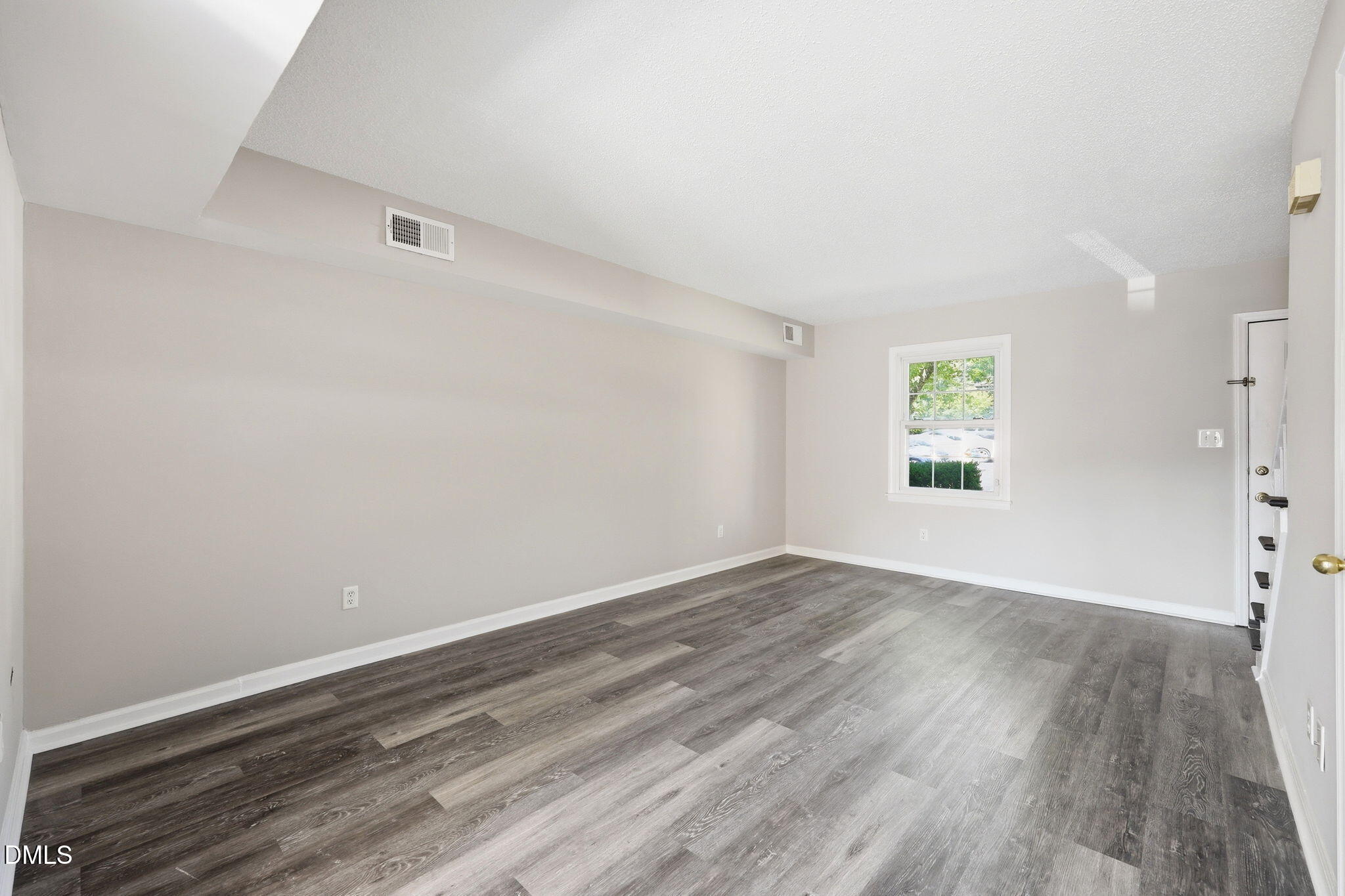 145 Jones Franklin Road, Unit D Raleigh, NC 27606 - Photo 3 of 23 an empty room with wooden floor and windows