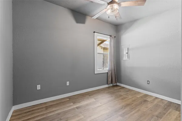 an empty room with chandelier fan and windows
