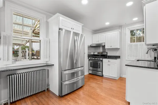 a kitchen with granite countertop a refrigerator and a stove top oven