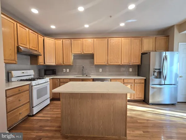 a large kitchen with stainless steel appliances granite countertop a refrigerator a stove a sink and a microwave