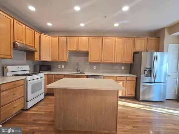 a large kitchen with stainless steel appliances granite countertop a stove a sink dishwasher and a refrigerator with wooden floor