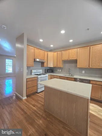 a large kitchen with kitchen island a large counter top space a sink stainless steel appliances and cabinets
