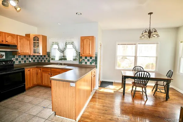 a kitchen with stainless steel appliances granite countertop a stove a sink a dining table and chairs with wooden floor