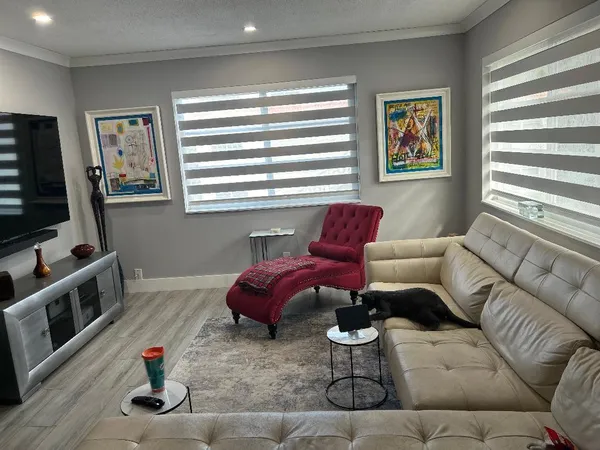 a living room with furniture a flat screen tv and a window