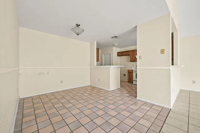 a view of an empty room with window and chandelier fan