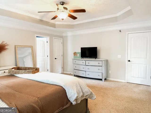a bedroom with a bed and a flat tv screen on a dresser