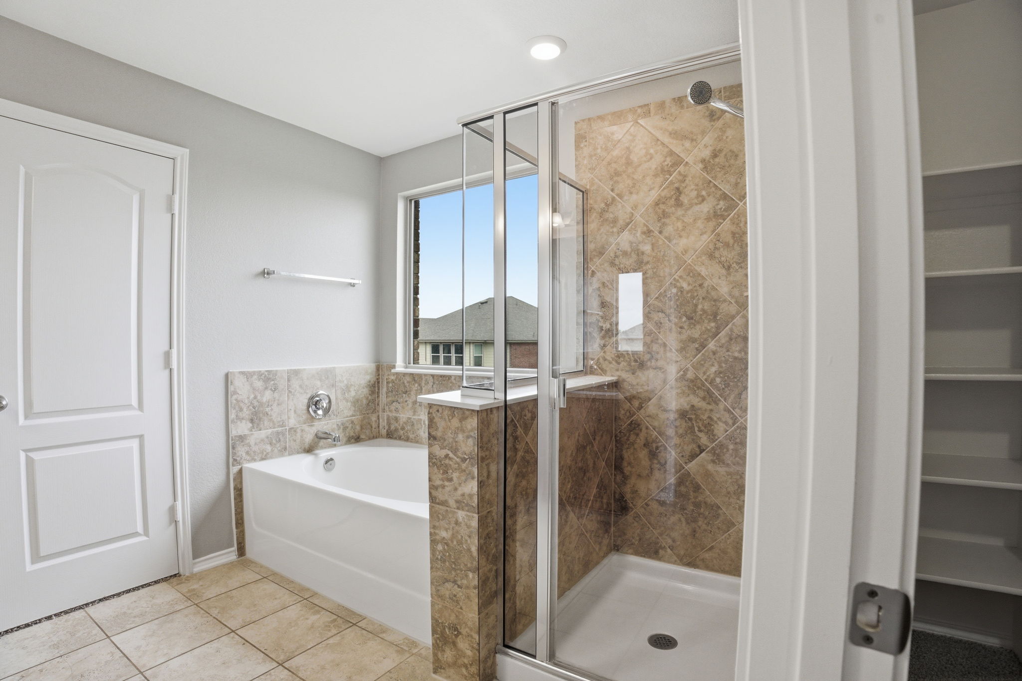 670 Landon Samuel Loop Pflugerville, TX 78660 - Photo 11 of 22 Bathroom featuring a built-in tub with tile surround, a separate glass-enclosed shower with tile walls, and a window for natural illumination
