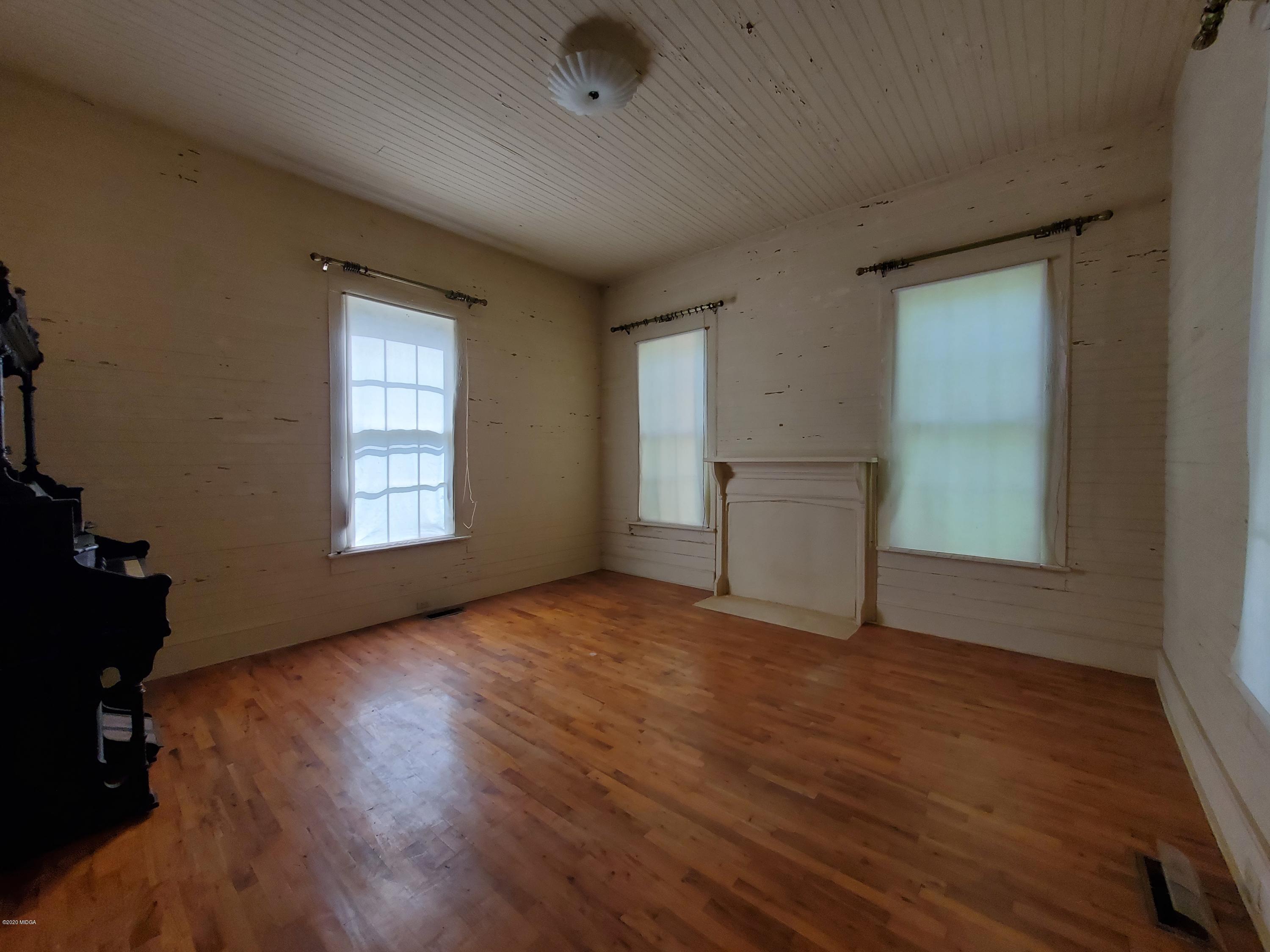 968 Rogers Church Road Forsyth, GA 31029 - Photo 10 of 14 an empty room with wooden floor cabinet and windows