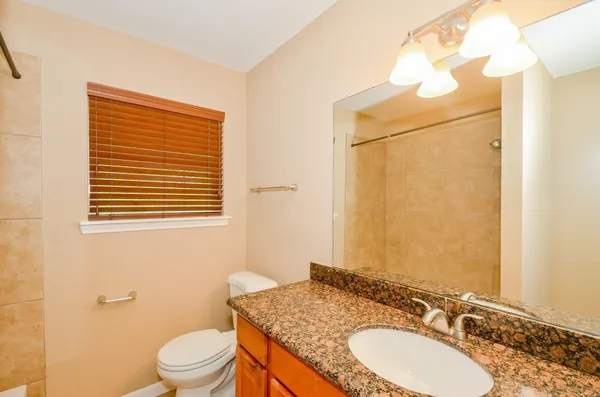 a bathroom with a granite countertop sink toilet and a mirror