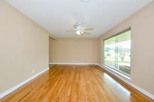 an empty room with wooden floor and windows