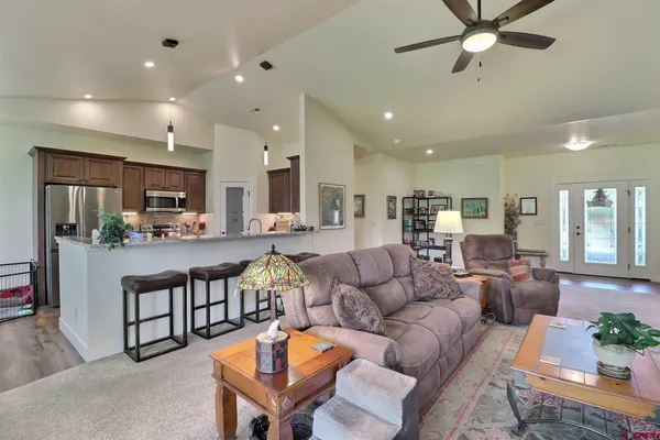 a living room with furniture kitchen view and a window
