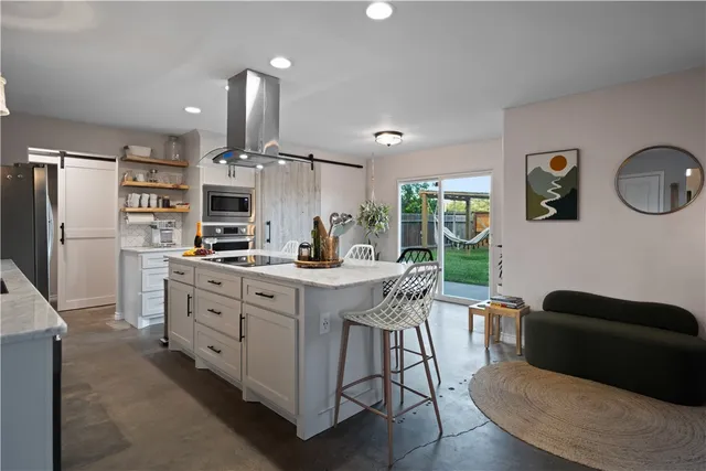 a kitchen with stainless steel appliances granite countertop a table chairs and a refrigerator