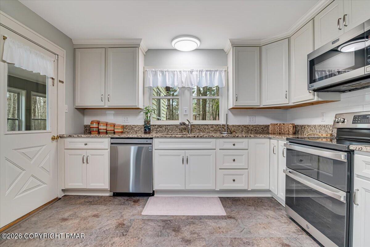 253 Thomas Road Blakeslee, PA 18610 - Photo 15 of 63 a kitchen with granite countertop white cabinets stainless steel appliances a sink and a window