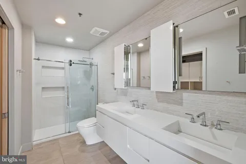 a bathroom with a double vanity sink toilet mirror and shower