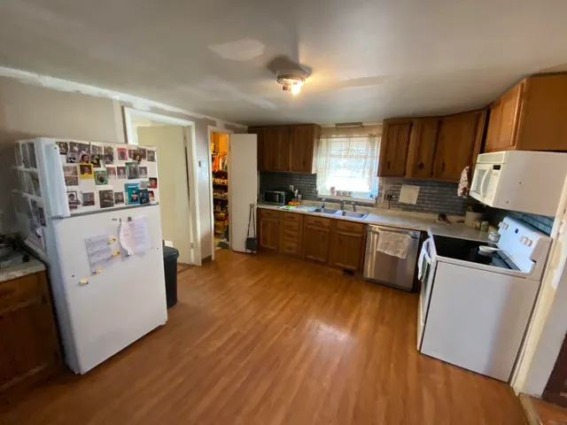 a kitchen with stainless steel appliances a stove a sink a refrigerator cabinets and wooden floor