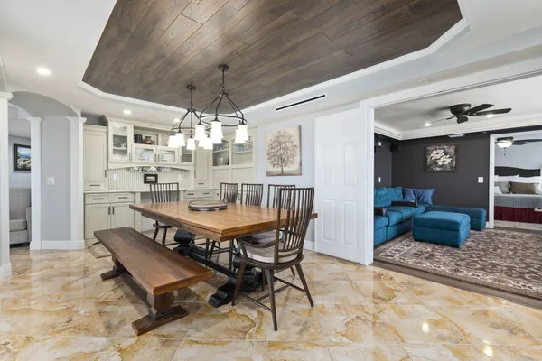 a dining room with chandelier and wooden floor
