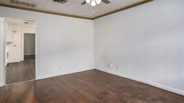 an empty room with a ceiling fan and wooden floor