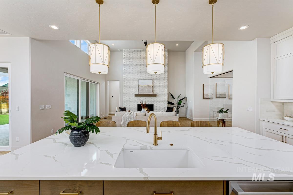 7026 Saddle Bred Way Star, ID 83669 - Photo 13 of 49 Kitchen with a center island with sink, light stone counters, a high ceiling, a brick fireplace, and hanging light fixtures