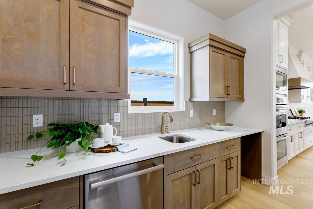 7026 Saddle Bred Way Star, ID 83669 - Photo 14 of 49 Kitchen featuring stainless steel appliances, light stone countertops, light wood-style flooring, extractor fan, and two tone color scheme