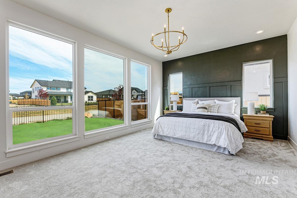 7026 Saddle Bred Way Star, ID 83669 - Photo 16 of 49 Carpeted bedroom featuring hanging lights, an accent wall, and a residential view