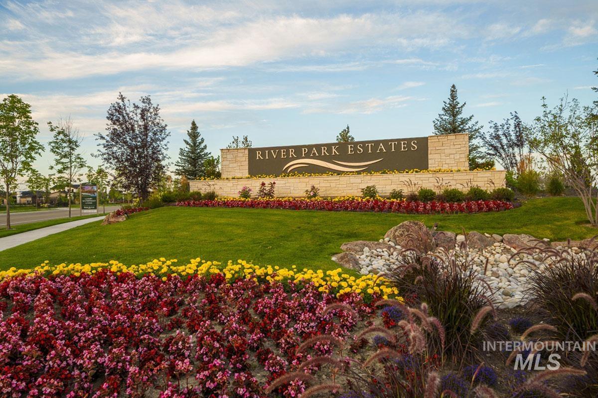 7026 Saddle Bred Way Star, ID 83669 - Photo 49 of 49 River Park Estates community entrance featuring stone-clad signage, vibrant floral landscaping, manicured green lawn, and mature trees