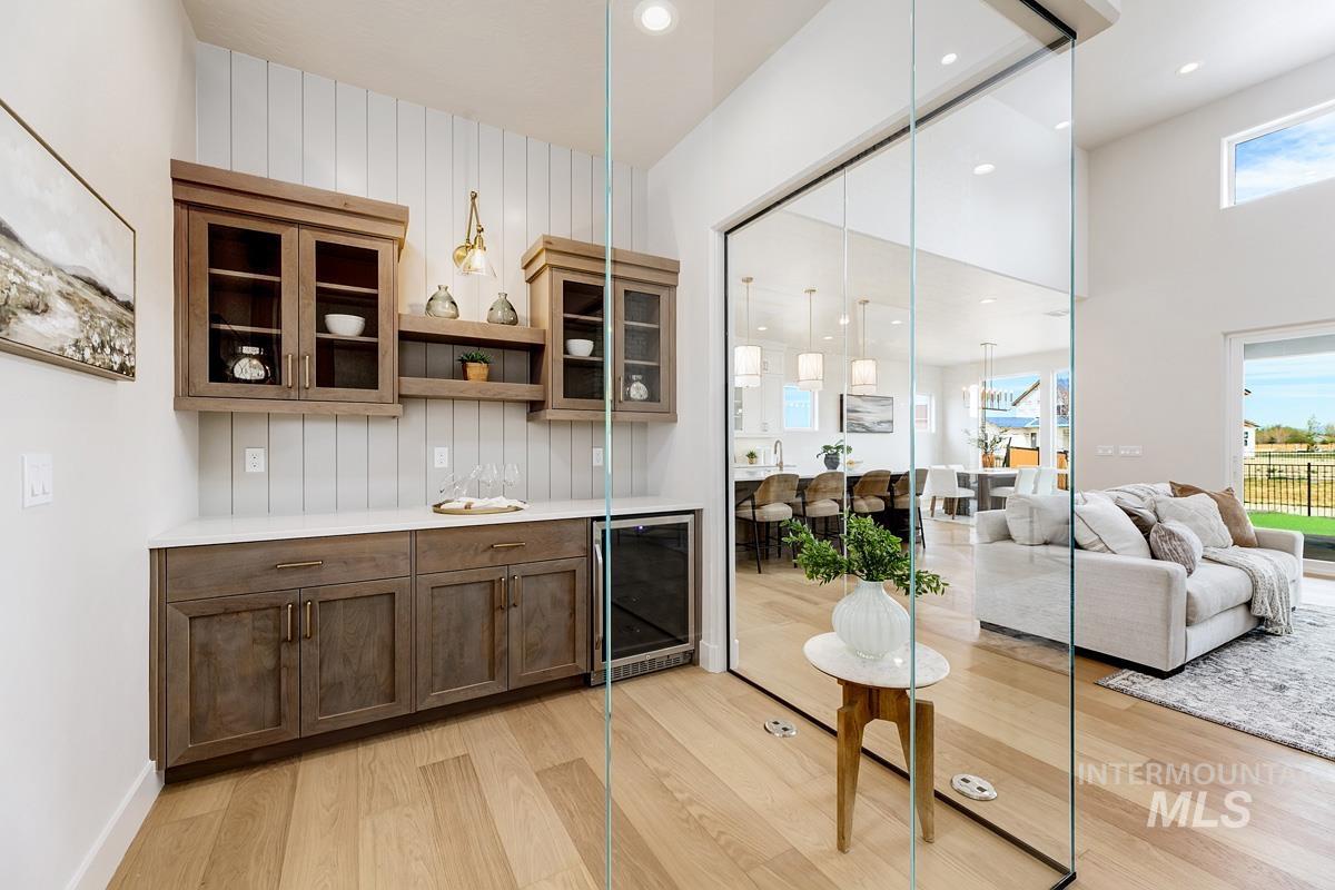 7026 Saddle Bred Way Star, ID 83669 - Photo 8 of 49 Indoor dry bar featuring glass insert cabinets, open shelves, light wood finished floors, wine cooler, and pendant lighting