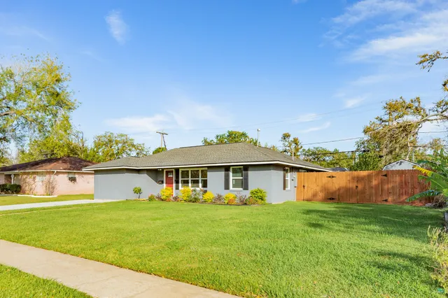 a front view of house with yard and trees in the background