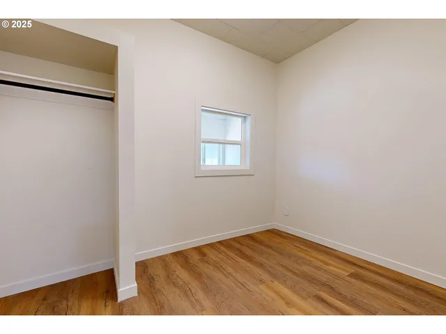 an empty room with wooden floor and window