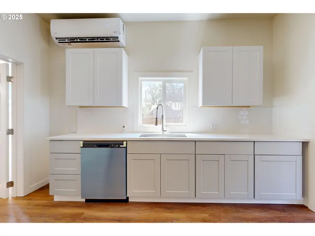 a kitchen with granite countertop a sink cabinets and a wooden floor
