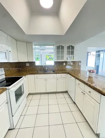 a kitchen with granite countertop a sink a stove a microwave and cabinets