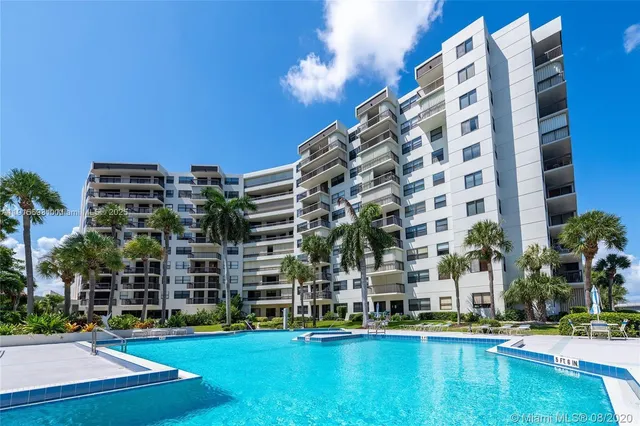a view of a swimming pool with a lawn chairs and palm trees