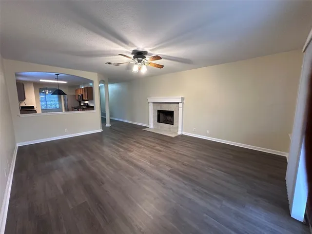 a view of an empty room with wooden floor and a ceiling fan