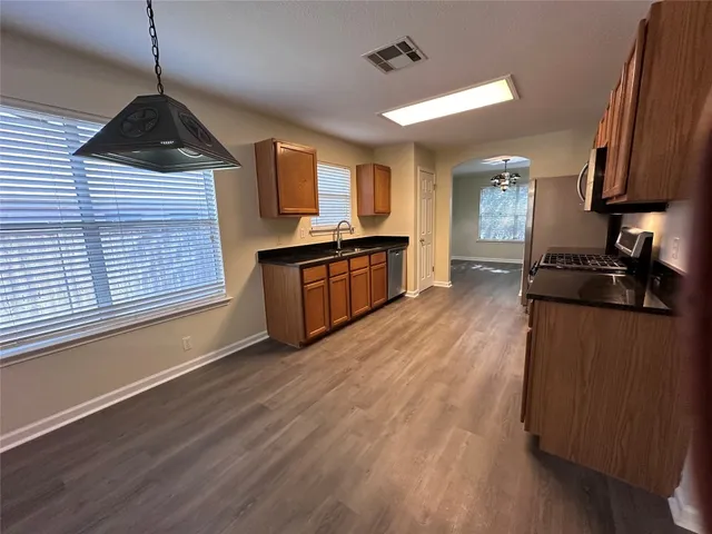 a kitchen with granite countertop wooden floors a stove and a window