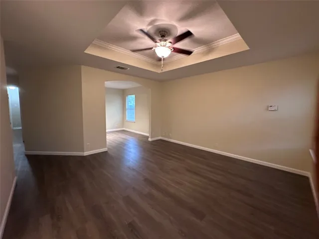 a view of an empty room with wooden floor and a ceiling fan
