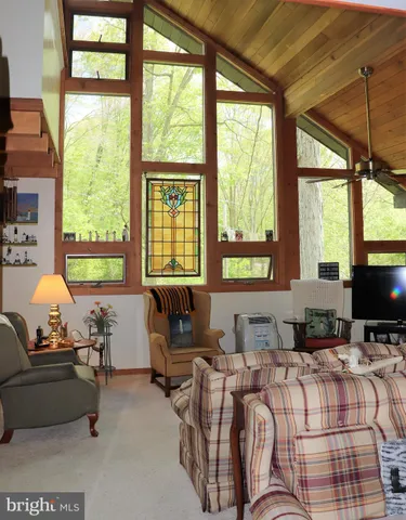 a living room with furniture a flat screen tv and a floor to ceiling window