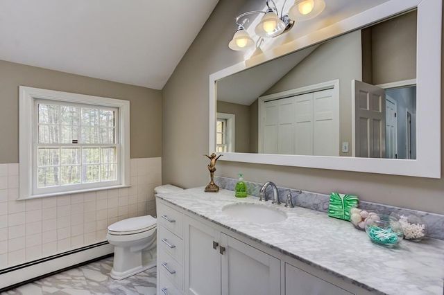a bathroom with a granite countertop sink a toilet and a mirror