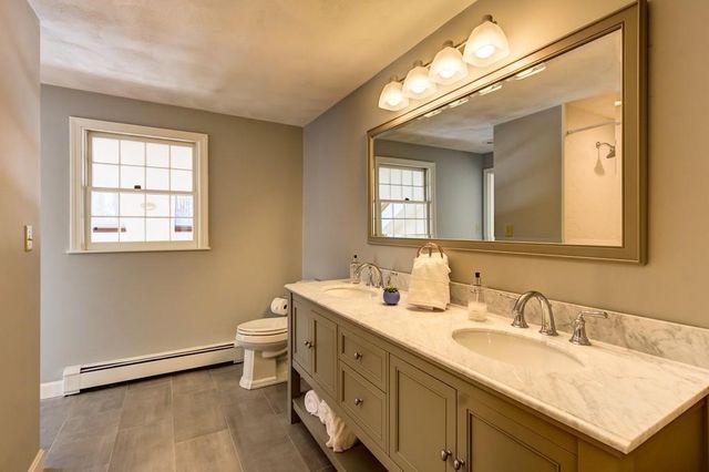 a bathroom with a granite countertop sink mirror and a toilet